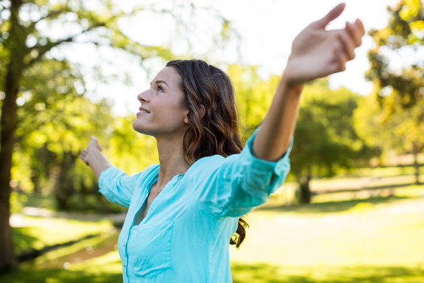 Nainen seisoo kädet ojennettuina puistossa
 - Valokuva, kuva