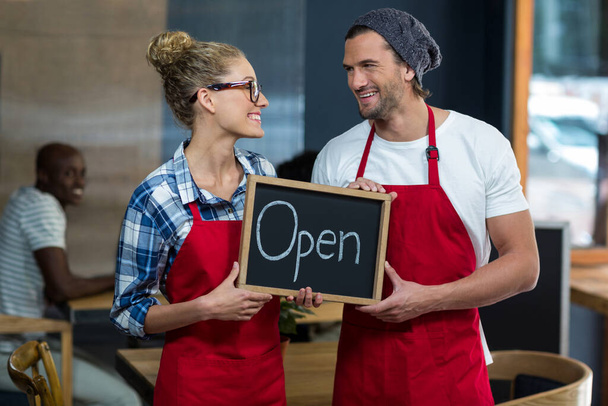 Cameriera e cameriere in piedi con cartello aperto nel caffè
 - Foto, immagini