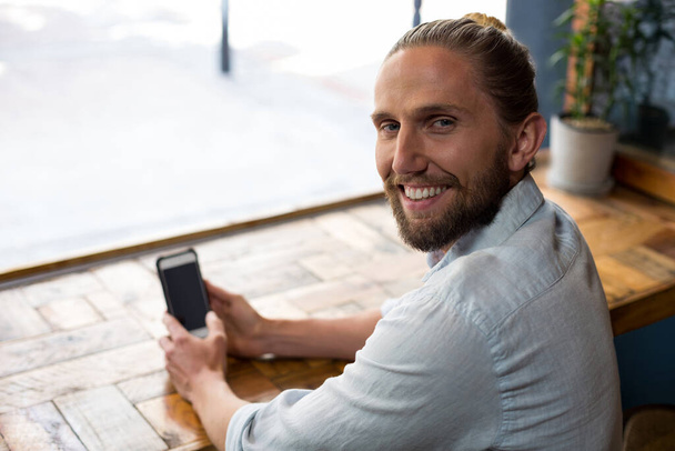 Smiling man using mobile phone at cafe - Fotoğraf, Görsel