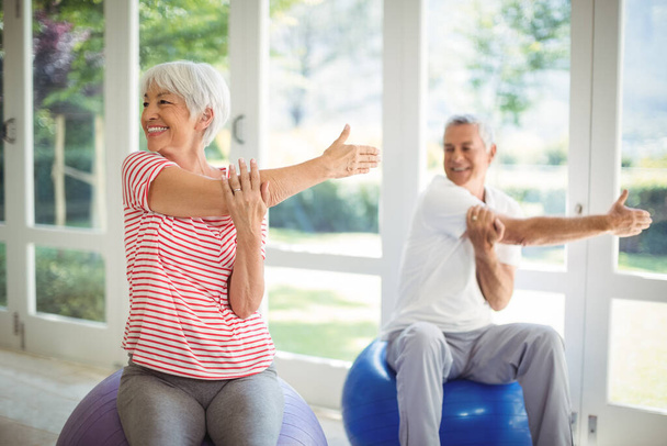 "Senior couple performing stretching exercise on fitness ball" - Valokuva, kuva