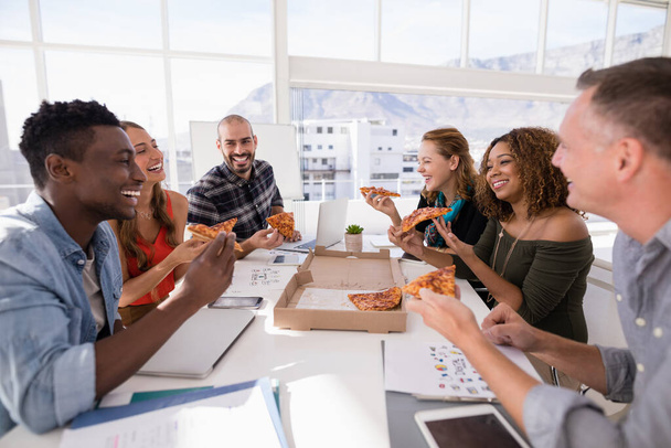 Happy manažeři sdílení pizzy v konferenční místnosti - Fotografie, Obrázek