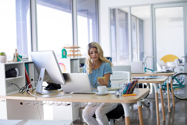 Жіночий керівник робить онлайн-покупки на ноутбуці за її столом - Фото, зображення