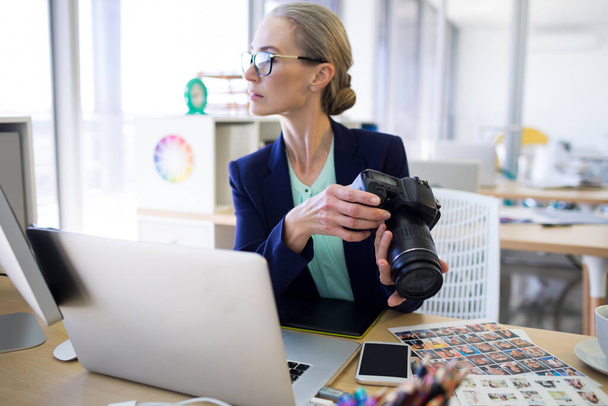 Žena výkonný drží digitální fotoaparát u svého stolu - Fotografie, Obrázek