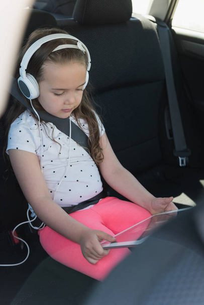 Dijital tabletten kulaklıkla müzik dinleyen tatlı kız.  - Fotoğraf, Görsel