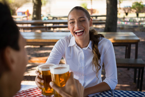 Χαρούμενη γυναίκα με φίλο που κάνει πρόποση για μπύρα - Φωτογραφία, εικόνα