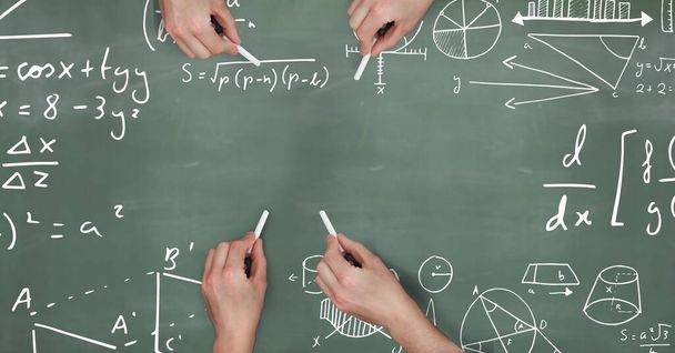 Handen met krijt met wiskundige vergelijkingen op schoolbord - Foto, afbeelding