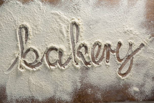 das Wort Bäckerei auf bestreutem Mehl geschrieben - Foto, Bild