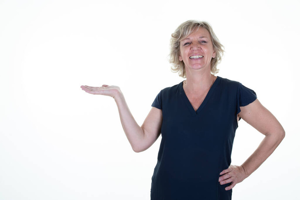 senior woman shows store promo deal smiles positively points at copy space isolated over white background - Photo, Image