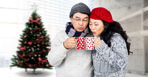 Χειμερινό ζευγάρι πίνοντας φλιτζάνια δίπλα στο χριστουγεννιάτικο δέντρο  - Φωτογραφία, εικόνα