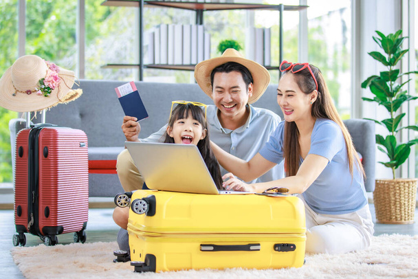 Millennial Azji piękny szczęśliwy rodzina ojciec matka i młoda dziewczynka córka pomagając pakowanie rzeczy w bagażu wózka przygotowując się do podróży na letnie wakacje rezerwacji hotelu i biletu lotniczego. - Zdjęcie, obraz