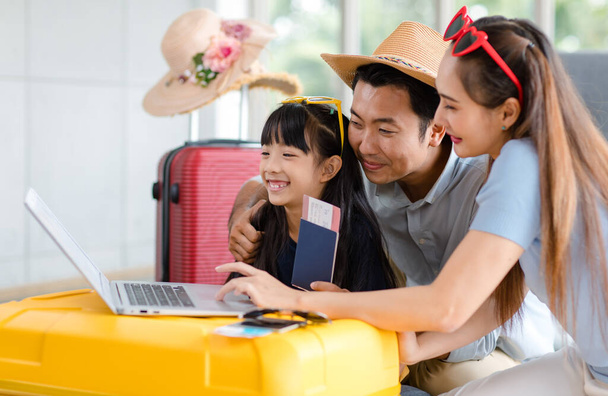 Millennial Asian lovely happy family father mother and young little girl daughter helping packing stuff in trolley luggage preparing to travel on summer vacation reserving hotel and airplane ticket. - Photo, Image