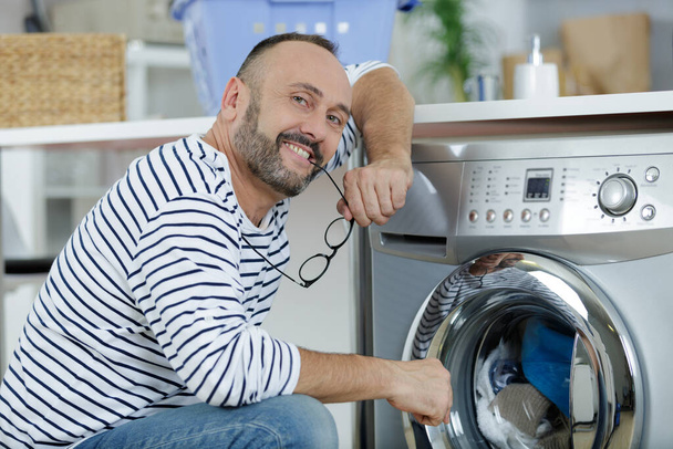 man loading clothes into washing machine - Foto, Imagem