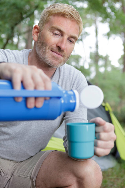 thoughtful travele drinks coffee from a thermos - Foto, Bild