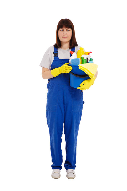 επαγγελματική έννοια υπηρεσία καθαρισμού - πορτρέτο της νεαρής γυναίκας καθαρότερο σε μπλε στολή με τον εξοπλισμό καθαρισμού που απομονώνονται σε λευκό φόντο - Φωτογραφία, εικόνα