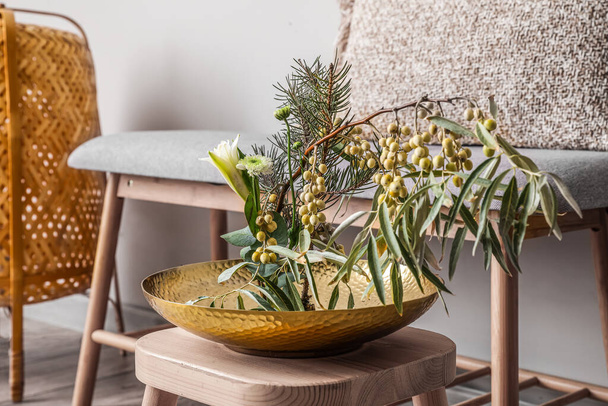 Bowl with beautiful ikebana on stool in light room, closeup - Zdjęcie, obraz
