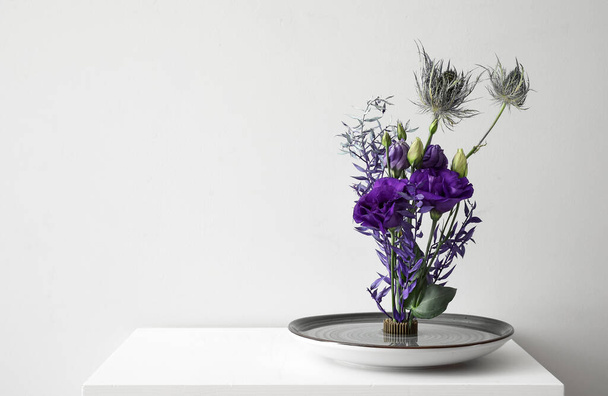 Schüssel mit schönem Ikebana auf Tisch neben Lichtwand - Foto, Bild