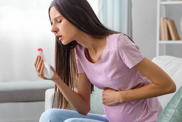 Young pregnant woman with nosebleed and tissue at home - Foto, imagen