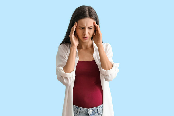 Young pregnant woman with nosebleed on blue background - Fotó, kép