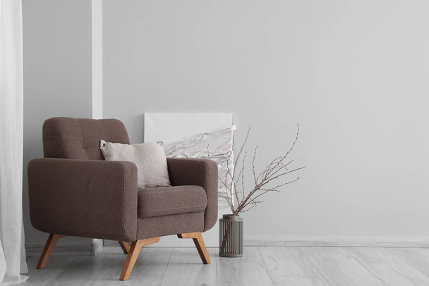 Elegante sillón y almohada cerca de la pared de luz en la habitación - Foto, Imagen
