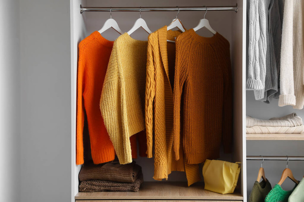 Warm gestrickte Pullover hängen im Kleiderschrank - Foto, Bild