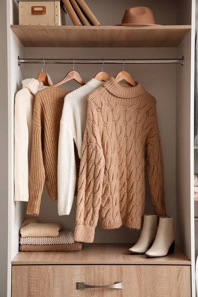 Теплые вязаные свитера, висящие в шкафу - Фото, изображение