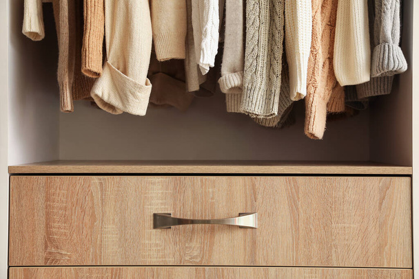 Ζεστά πλεκτά πουλόβερ που κρέμονται στην ντουλάπα, closeup - Φωτογραφία, εικόνα