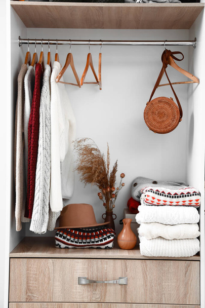 ワードローブの棚に暖かいニットセーター、帽子、バッグ、花瓶 - 写真・画像
