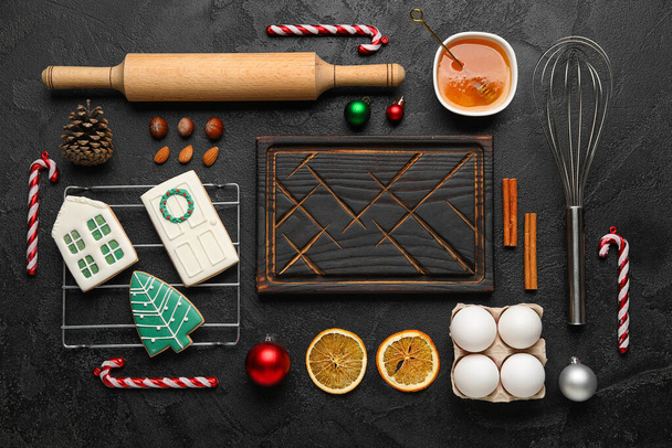 Состав с деревянной доской и ингредиентами для приготовления рождественских печенек на темном фоне - Фото, изображение