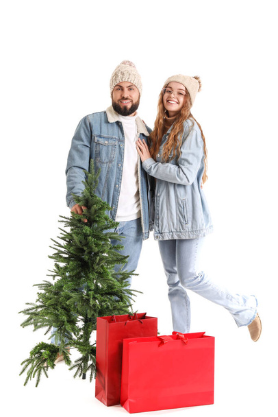 Young couple with Christmas tree and shopping bags on white background - Photo, Image