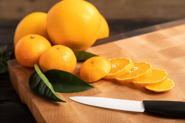 rebanadas de naranja y otras frutas en una tabla de cortar de madera - Foto, imagen