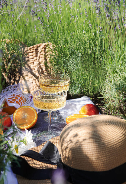 Καλοκαιρινό πικνίκ σε χωράφι με λεβάντα με ποτήρια σαμπάνιας και φρούτα - Φωτογραφία, εικόνα