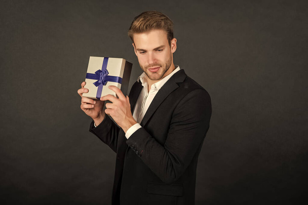 young man in suit showing birthday present box. - Zdjęcie, obraz