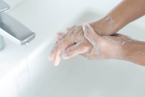 Мытье рук крупным планом с мылом в ванной комнате, избирательный фокус - Фото, изображение