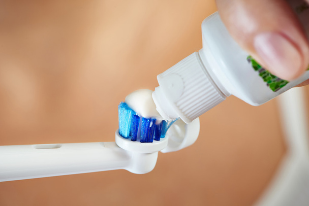 Hands squeezing toothpaste on electric toothbrush macro - Foto, Imagem
