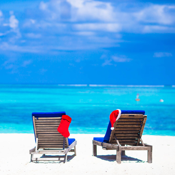 赤のクリスマス ストッキングと白いトロピカルビーチで椅子のサンタ帽子 - 写真・画像