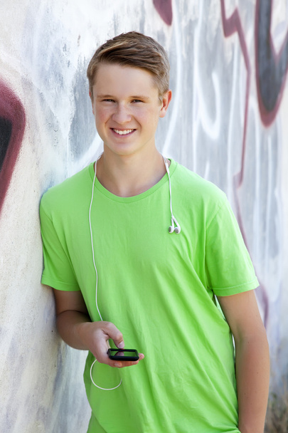 Niño adolescente con auriculares cerca de la pared de graffiti
. - Foto, Imagen