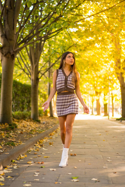 Portrait of a caucasian brunette woman in autumn, walking through a natural park in the city, autumnal lifestyle - 写真・画像