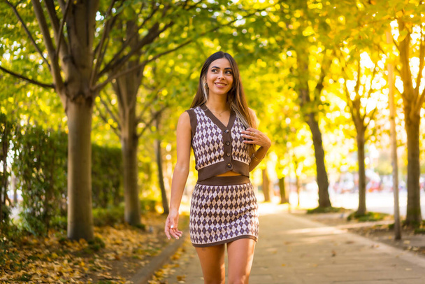 A caucasian brunette woman in autumn walking through a natural park in the city, autumn lifestyle - Foto, afbeelding