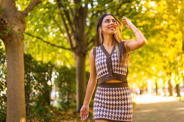 A caucasian brunette woman in autumn walking through a natural park in the city, autumn lifestyle - Φωτογραφία, εικόνα