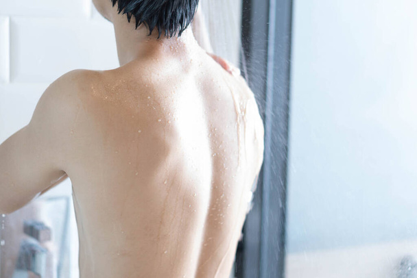 Gros plan beau asiatique homme prendre une douche dans la salle de bain - Photo, image