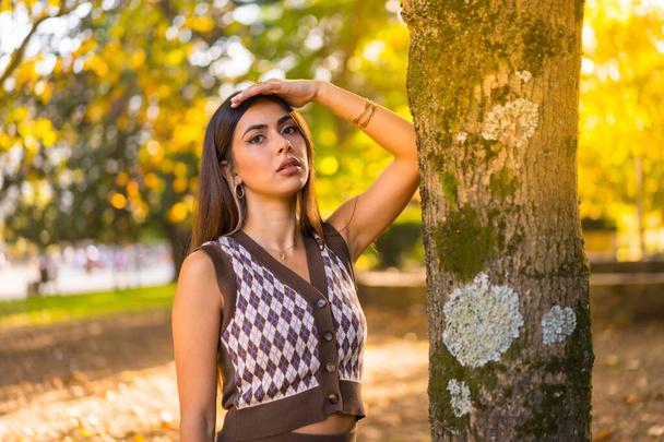 Brunette model in autumn at sunset in a natural city park, with the sun in the background - Fotografie, Obrázek