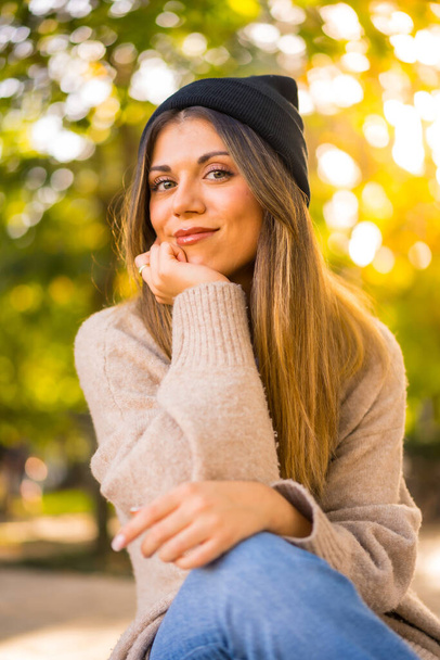 Young blonde girl in a woolen hat in autumn, sitting in the sunset - Foto, Imagem