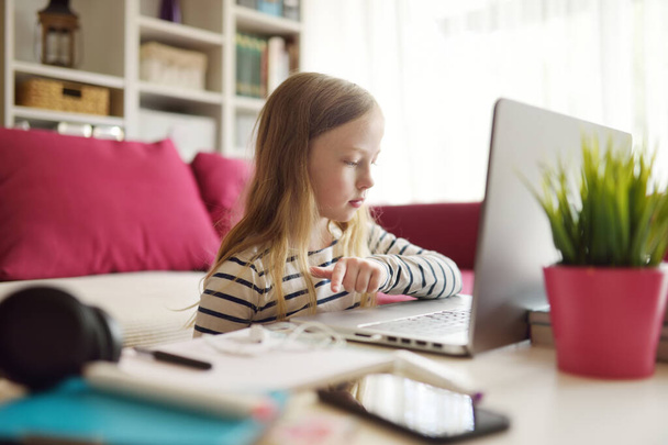 Jong schoolmeisje doet haar huiswerk met digitale tablet thuis. Kind dat gadgets gebruikt om te studeren. Onderwijs en afstandsonderwijs voor kinderen. Thuisonderwijs tijdens quarantaine. - Foto, afbeelding