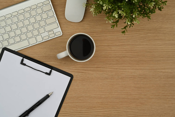 Kablosuz klavye, kahve fincanı, not panosu ve ahşap çalışma masasındaki saksı bitkisinin üst görüntüsü.. - Fotoğraf, Görsel