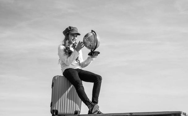 teen girl with globe and travel bag on sky background, copy space, traveling. - 写真・画像