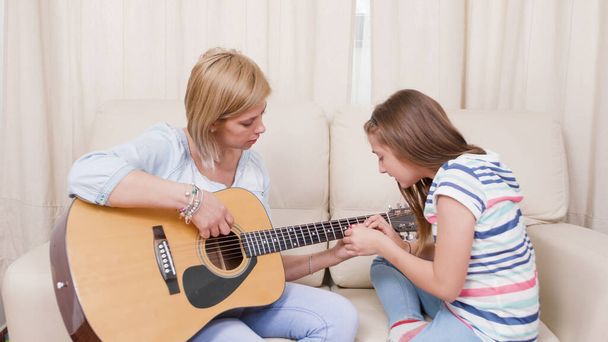 mother and daughter playing guitar at home - Photo, Image