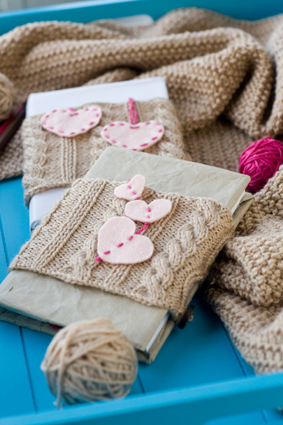 Two old pads in knitted cover with felt hearts lie next to the c - Photo, Image