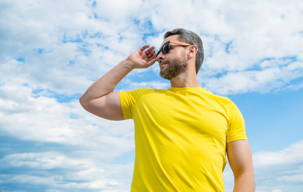 guy wearing yellow shirt and sunglasses outdoor on sky background. - Zdjęcie, obraz