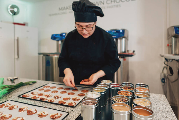 echte vrouwelijke meester chef chocolatier werken in ambachtelijke professionele chocolade laboratorium - Foto, afbeelding
