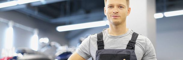 Portrait of qualified maintenance service worker in uniform, man with clipboard paper on motorbike background. Pit stop, garage, high quality help concept - 写真・画像